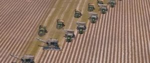 A group of tractors are in the middle of a field.